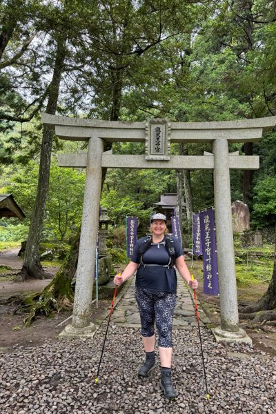 Happy traveller posing at a traditional Japanese torii gate on the Kumano Kodo pilgrimage trail